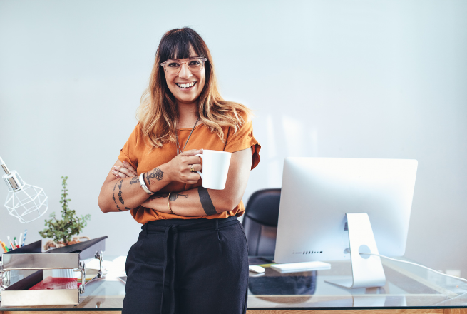 Frau mit einer Tasse an ihrem Arbeitsplatz